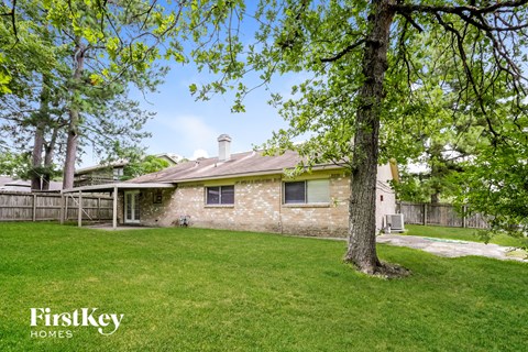 a backyard with a brick house and a tree