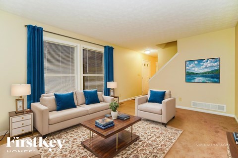 A living room with a couch, chair, and a painting on the wall.