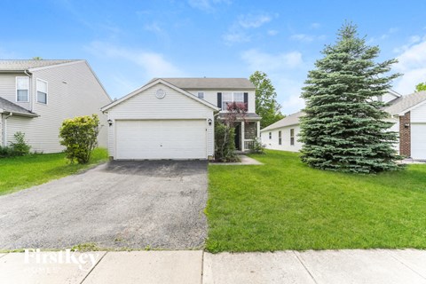 A house with a garage and a tree in front.