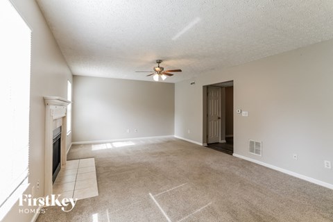 A spacious living room with a fireplace and a ceiling fan.