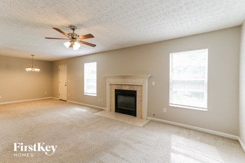 A spacious living room with a fireplace and a ceiling fan.