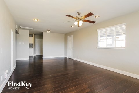 A spacious room with a ceiling fan and hardwood floors.