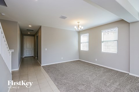 A spacious room with a carpeted floor and a chandelier hanging from the ceiling.