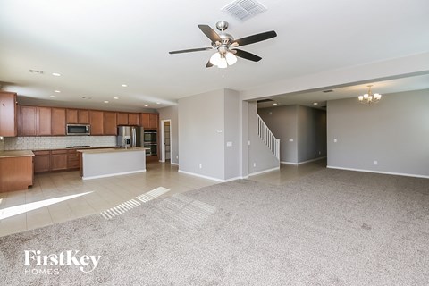A spacious living room with a kitchen area in the background.