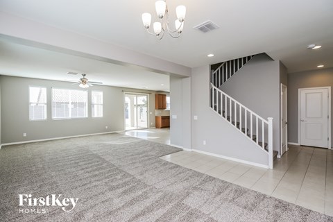 A spacious living room with a staircase and a rug on the floor.