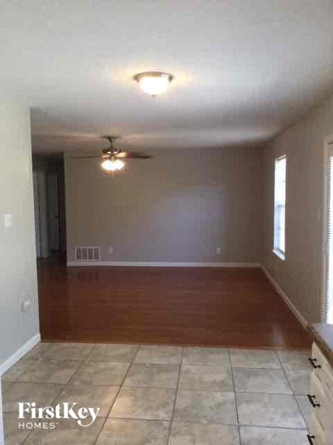 a empty living room with a ceiling fan and a tiled floor
