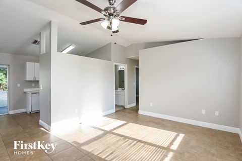 A spacious room with a ceiling fan and lighting fixture.