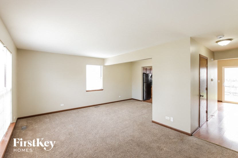 A spacious room with a carpeted floor and a window letting in natural light.