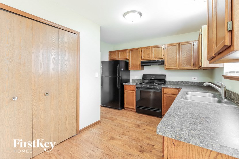 A kitchen with wooden cabinets and a black fridge.