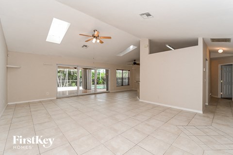 a empty living room with a ceiling fan and a tile floor
