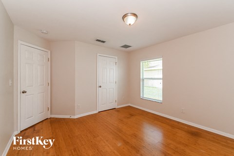 a bedroom with wood floors and white walls and two doors