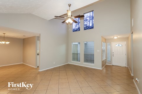 an empty living room with a ceiling fan and windows