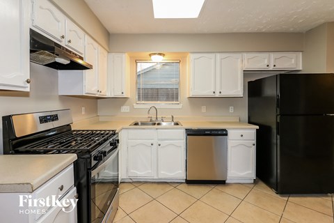 a kitchen with white cabinets and black appliances