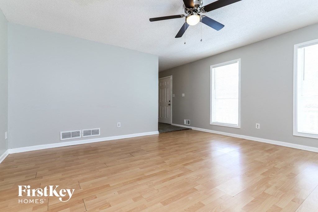 the living room and dining room with hardwood floors and a ceiling fan