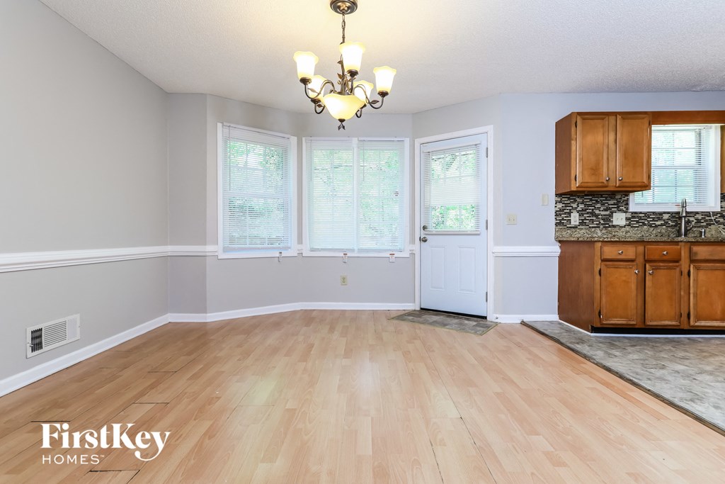 an empty kitchen and dining room with wood floors and a chandelier