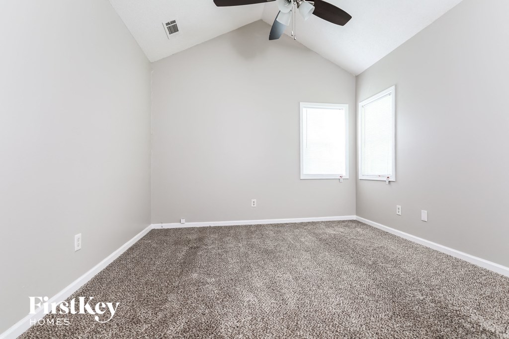 a empty room with carpet and a ceiling fan