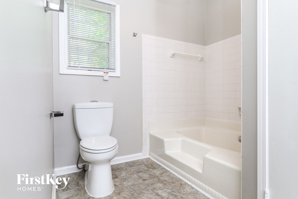 a bathroom with a toilet and a tub and a window