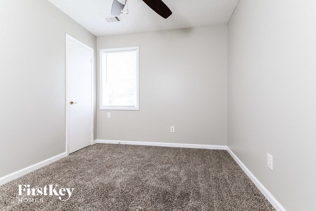 a carpeted room with white walls and a window