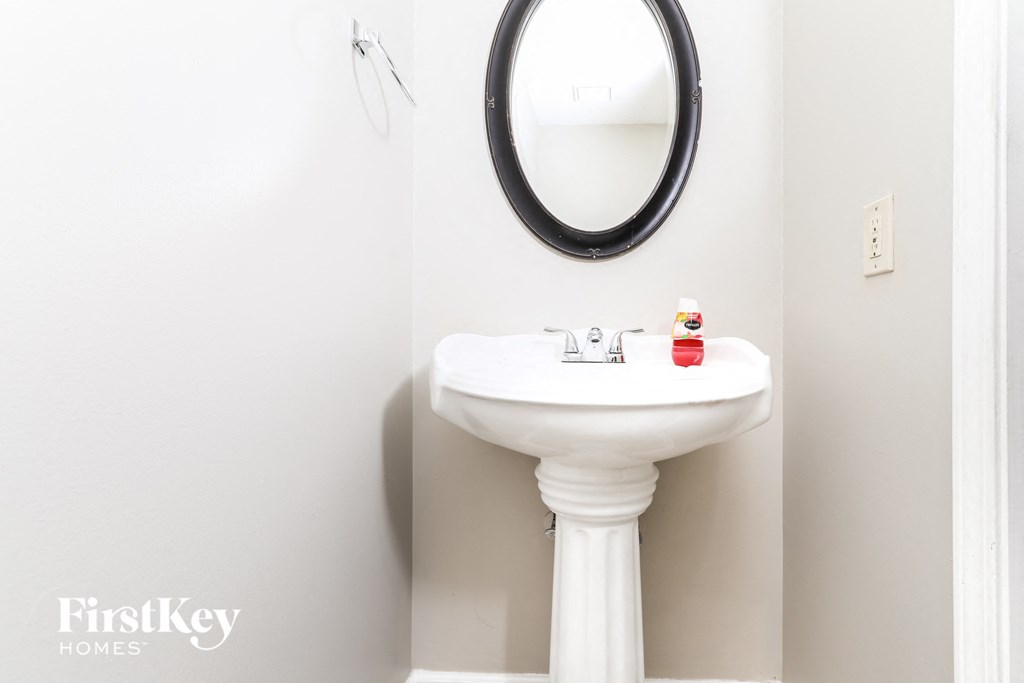 a small bathroom with a white sink and a black mirror