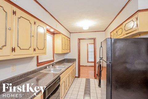 A kitchen with wooden cabinets and a black refrigerator.