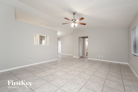 a spacious living room with tile flooring and a ceiling fan