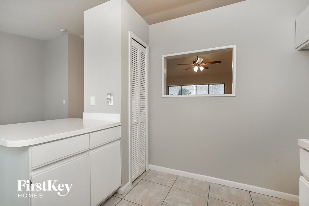 a laundry room with white cabinets and a ceiling fan