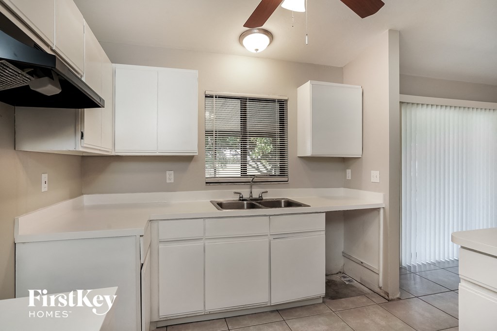 a kitchen with white cabinets and a sink and a window