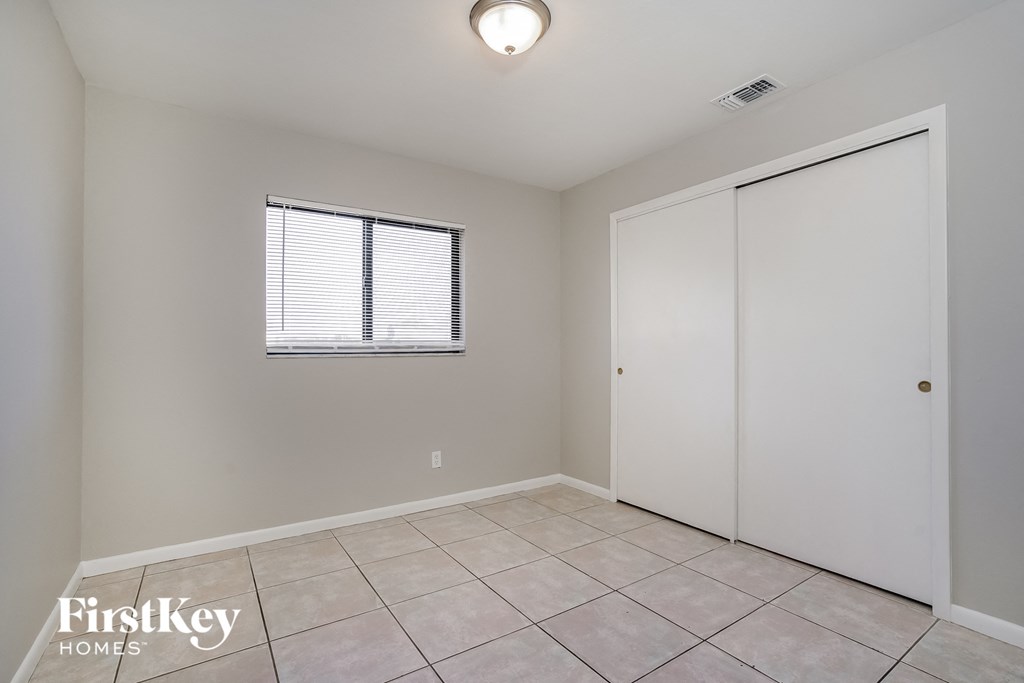 the living room of an empty home with a large tiled floor and a closet