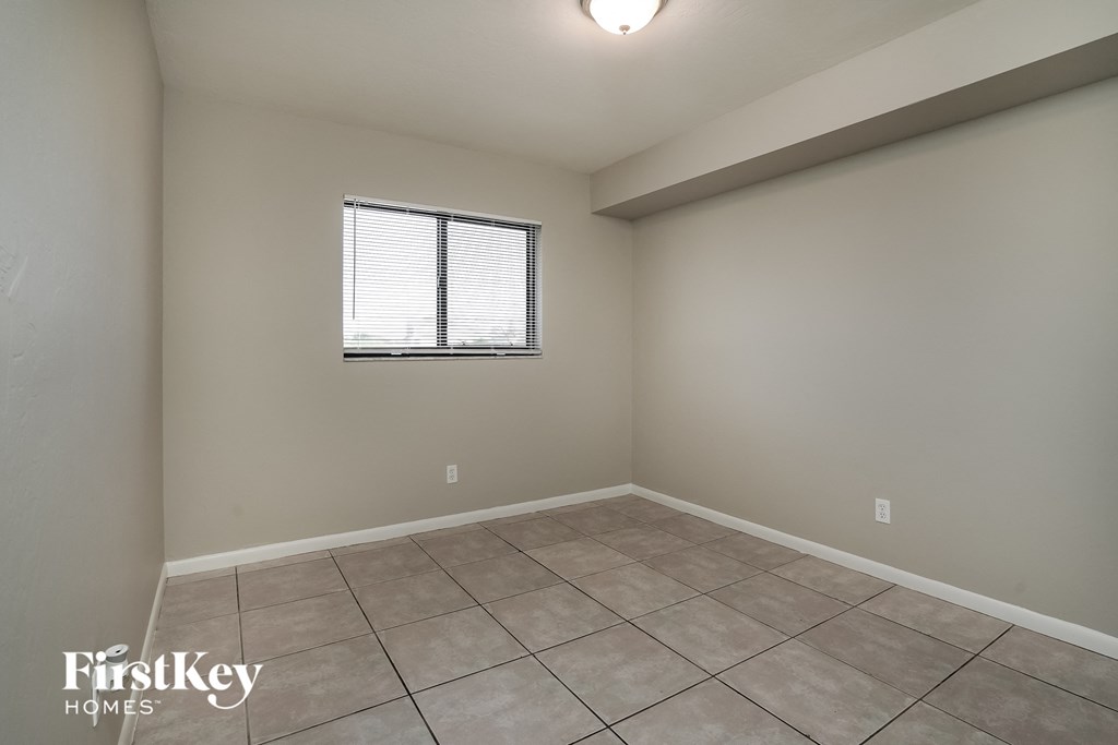 the spacious living room has tile flooring and a window