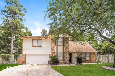 a white and brick house with a tree in front of it