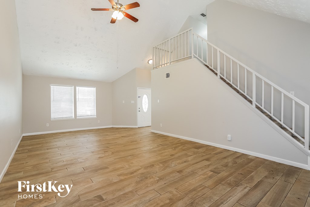 the spacious living room with wood floors and a staircase