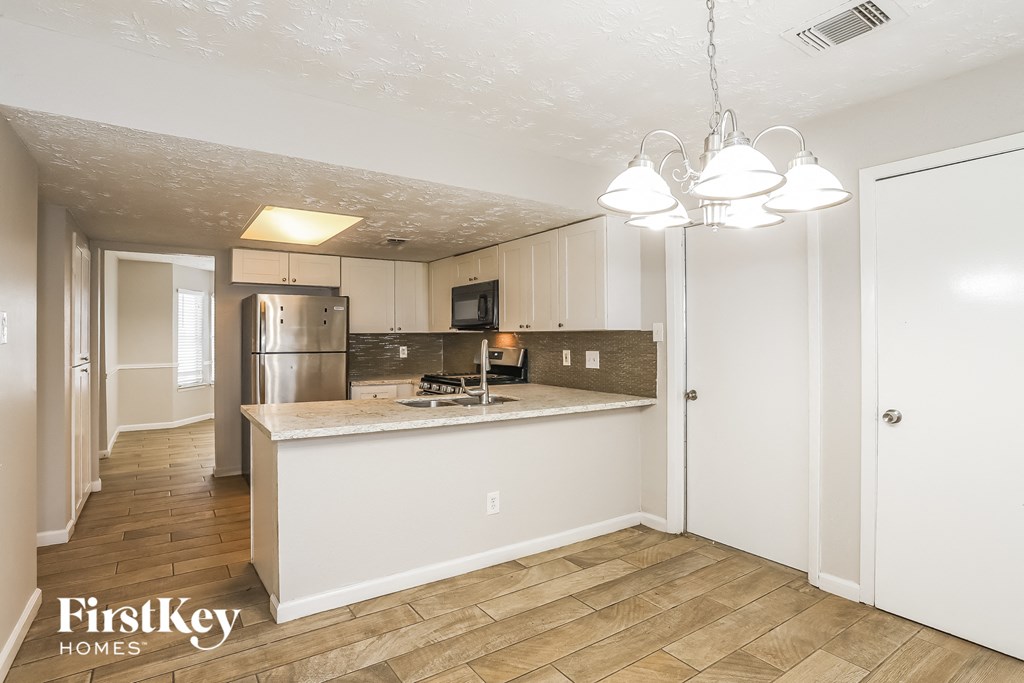 a kitchen with white cabinets and a counter top and a refrigerator