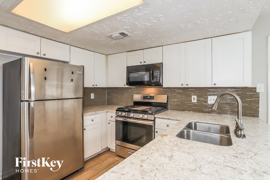 a kitchen with white cabinets and stainless steel appliances