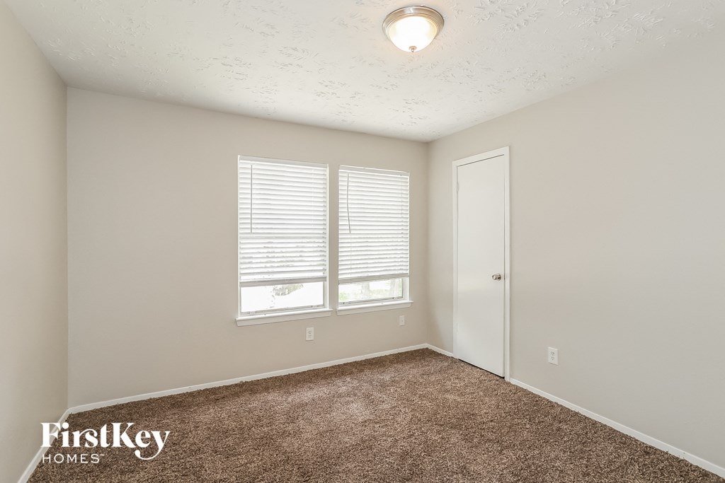 the spacious living room with carpet and a door to the bedroom