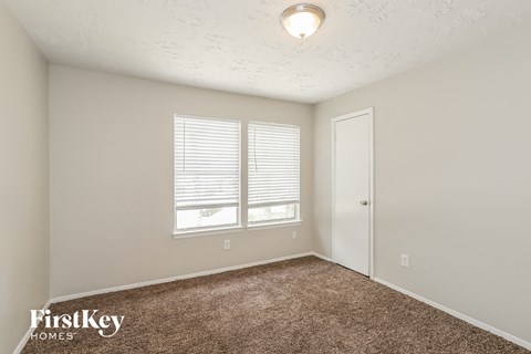 the spacious living room with carpet and a door to the bedroom