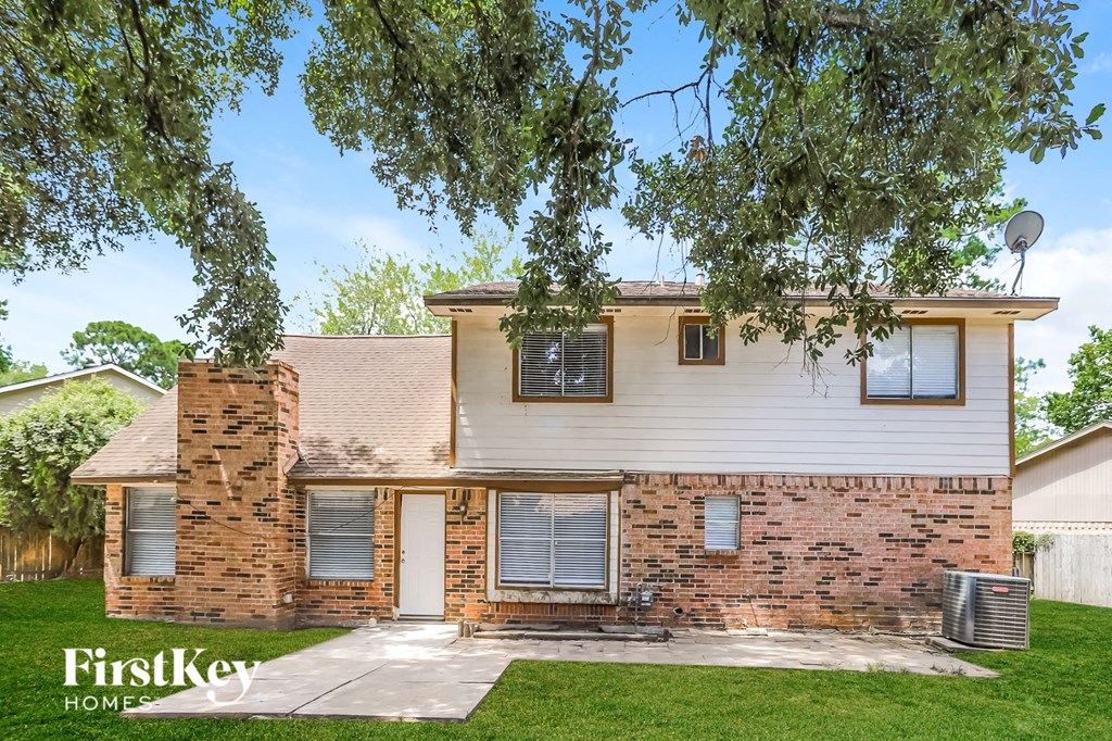 front view of a white and brick house with a yard and trees