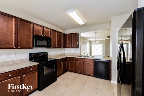 A kitchen with brown cabinets and black appliances.