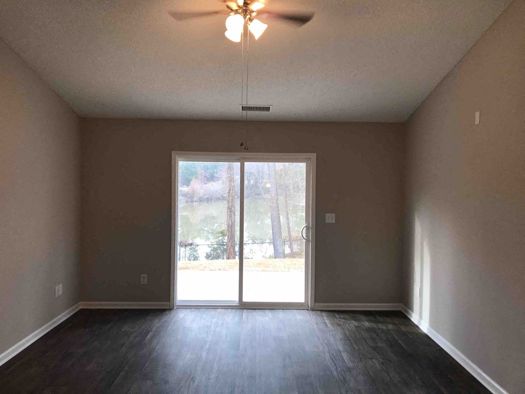 A room with a ceiling fan and sliding glass doors.