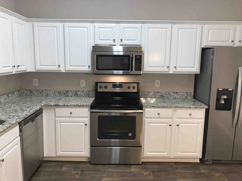 A kitchen with white cabinets and a granite countertop.