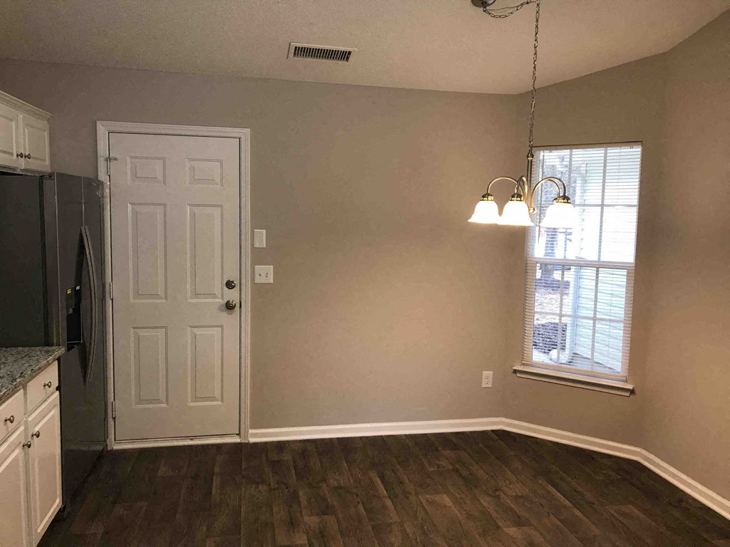 A kitchen with a white door and a window with blinds.