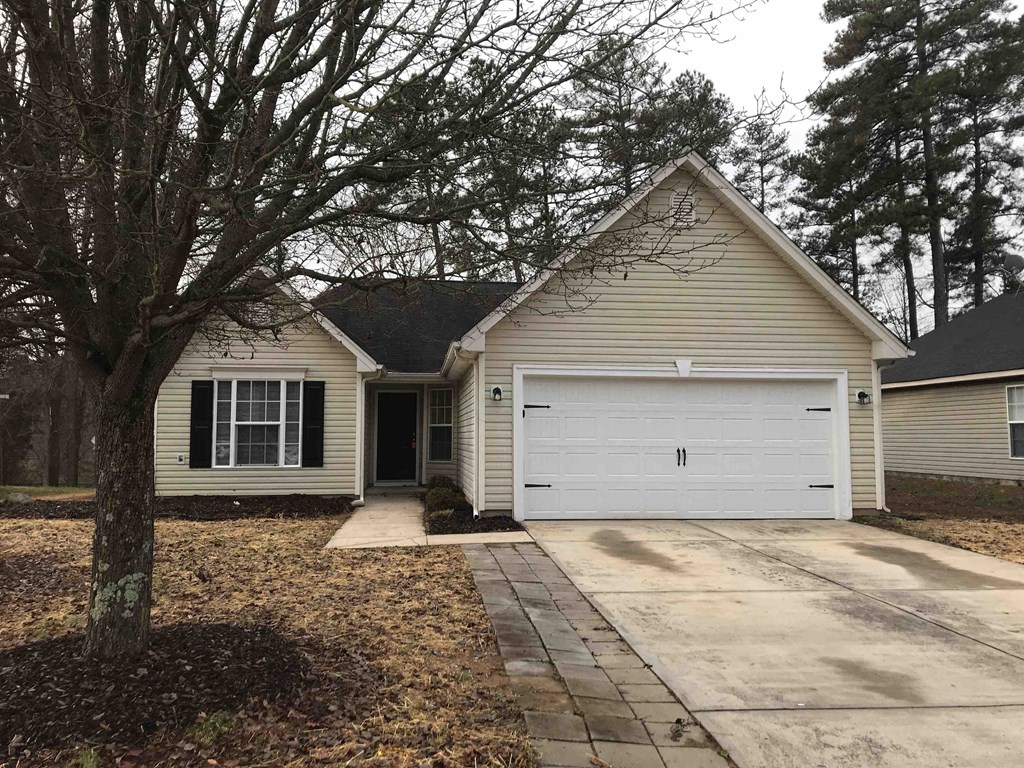 A house with a white garage door is surrounded by trees.