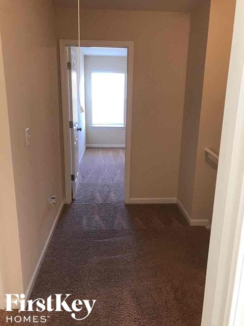 a hallway with a carpeted floor and a door to a bedroom