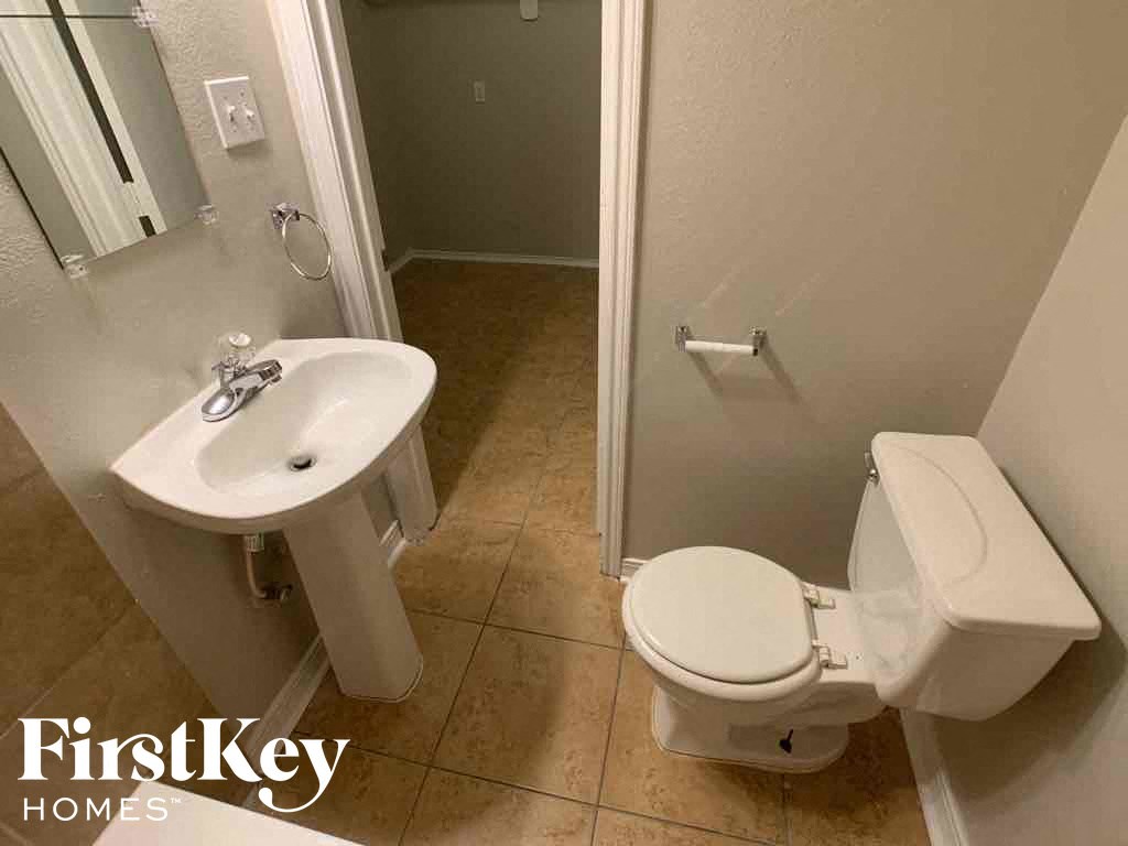 A white toilet with a white sink in a small bathroom.