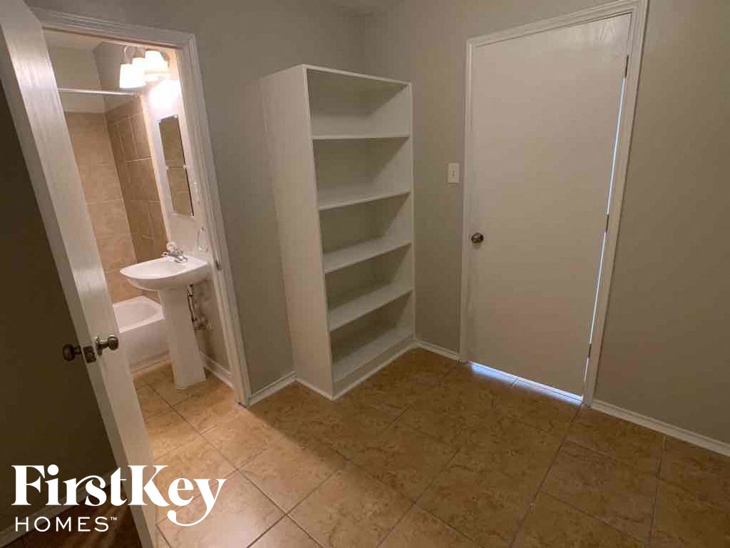A bathroom with a toilet, sink, and shelves.