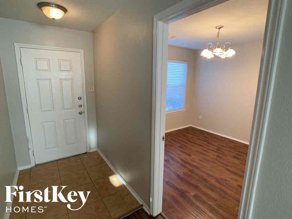 A room with a white door and wooden flooring.