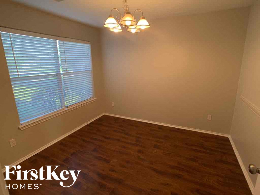 A room with wooden flooring and a window with blinds.