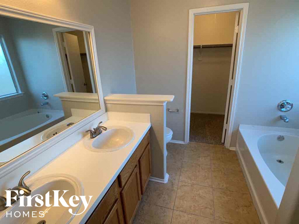 A bathroom with a sink, mirror, and bathtub.