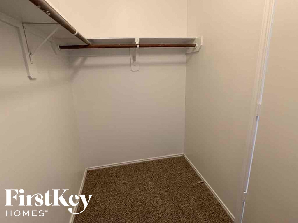 A small, empty room with a carpeted floor and a shelf above.