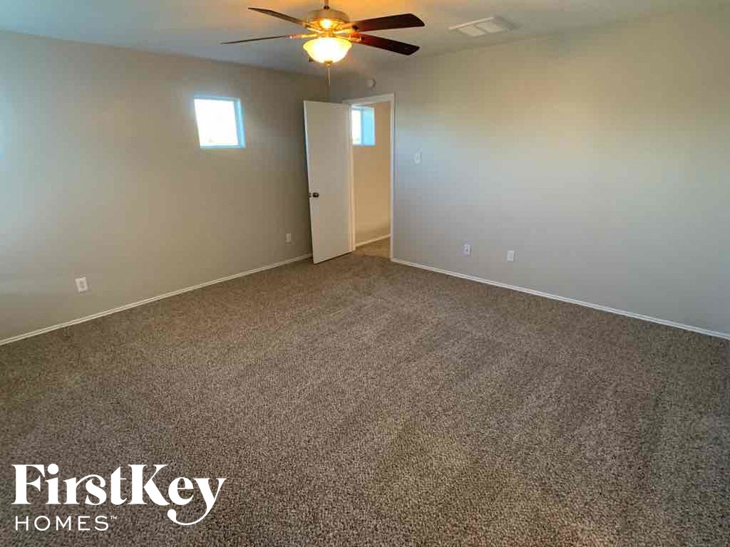 A room with a carpeted floor and a ceiling fan.