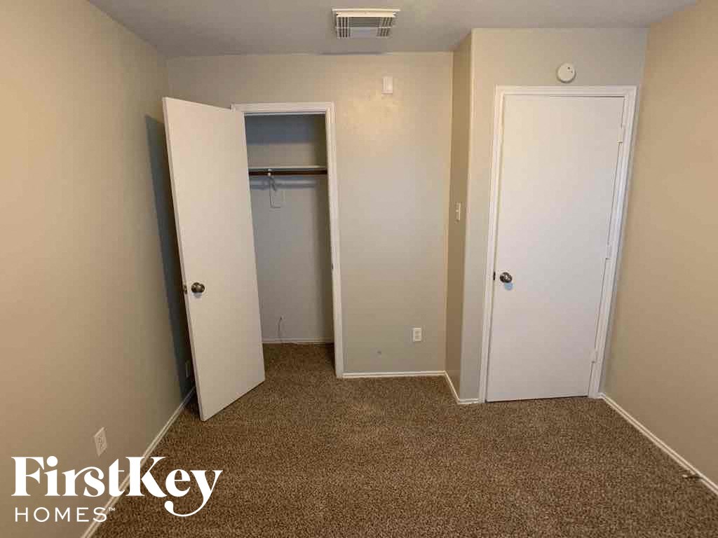A carpeted room with a door and a closet.